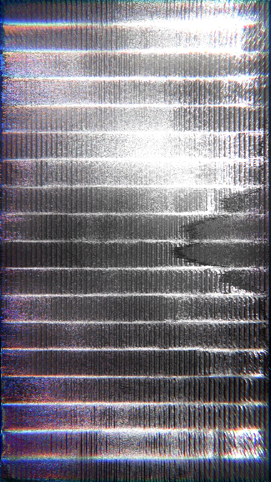 Vertical image of silver and grey metallic texture with fine vertical ridges, horizontal bands of light and rainbow fringes at the edges